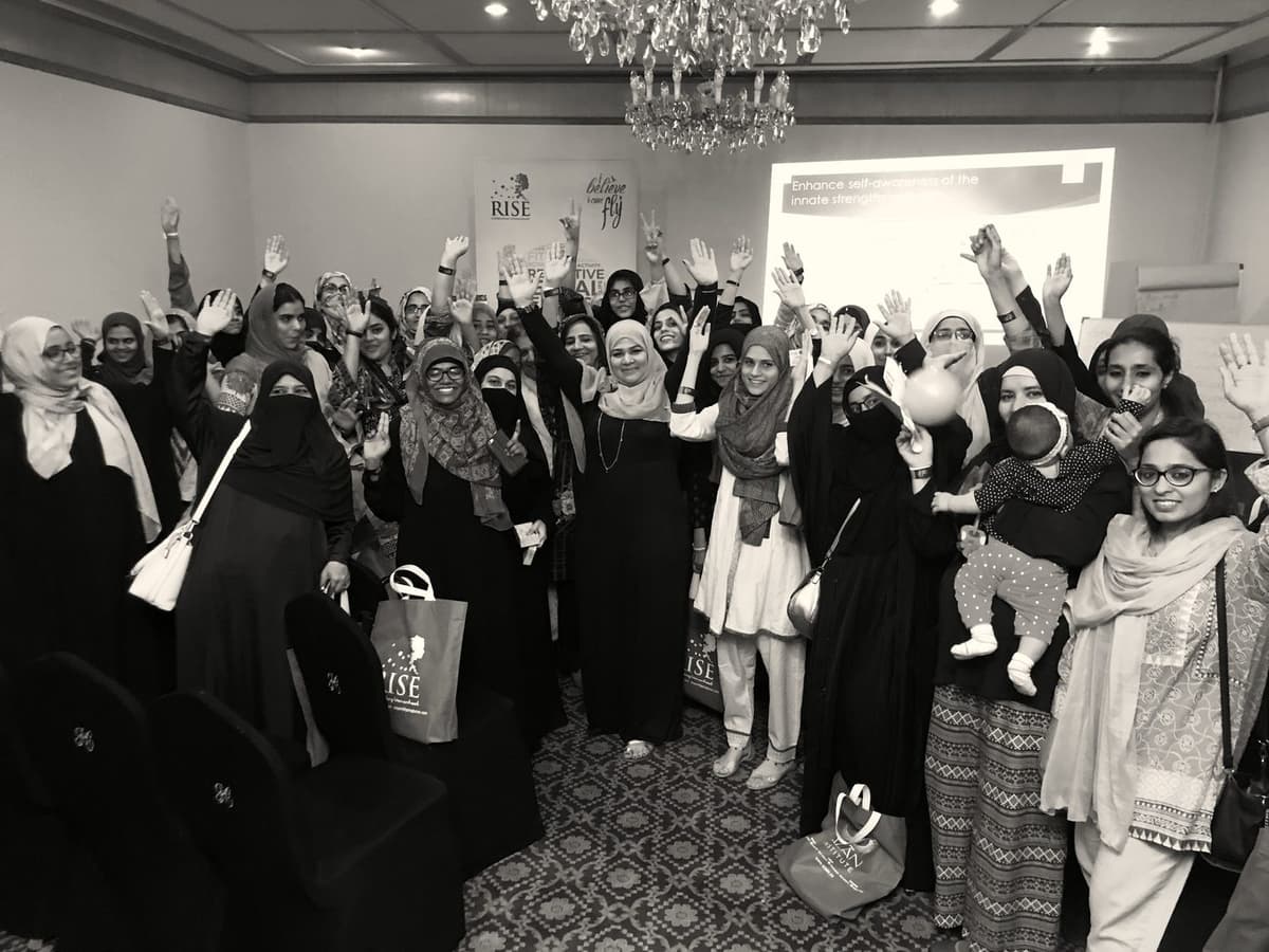 A She Rises workshop room, hands raised